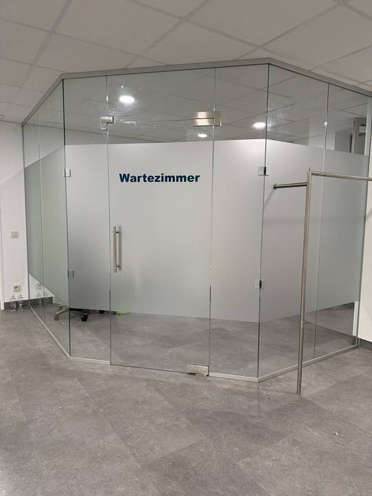 Glastrennwand in einem Gebäude mit Milchglasfolie und Beschriftung