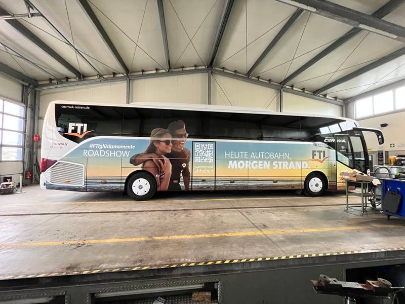 FTI-Reisebus mit großflächiger Werbefolierung in der Halle
